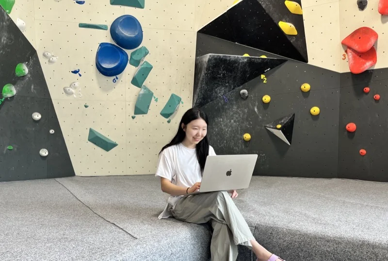 Lyla working on a laptop at a climbing gym